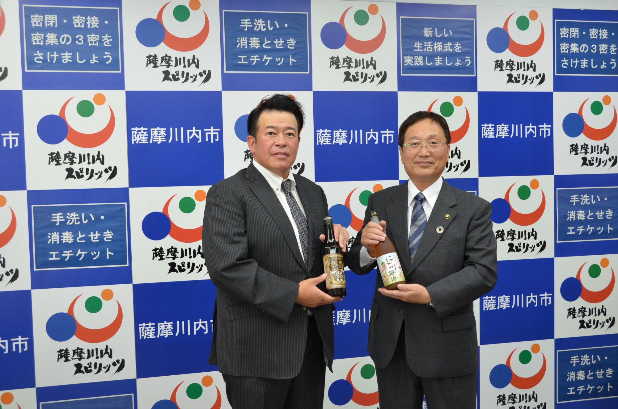 日本酒の瓶を持って立つスーツ姿の男性たちの写真