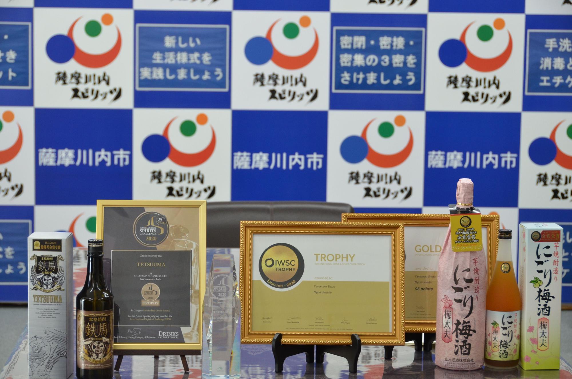 世界三大酒類コンテストの賞状と今回受賞した酒の「鉄馬」と「にごり梅酒」の写真