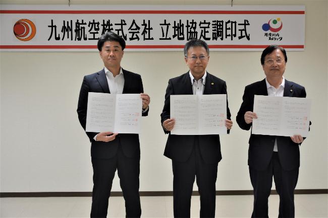 協定書を手に代表らと写真撮影をする田中市長