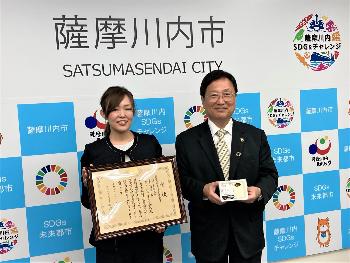 賞状と豆腐を手に記念撮影を行う北野取締役と田中市長