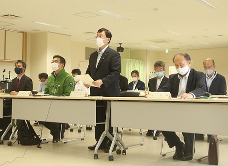 スーツを着た男性が椅子から立ち上がっている写真