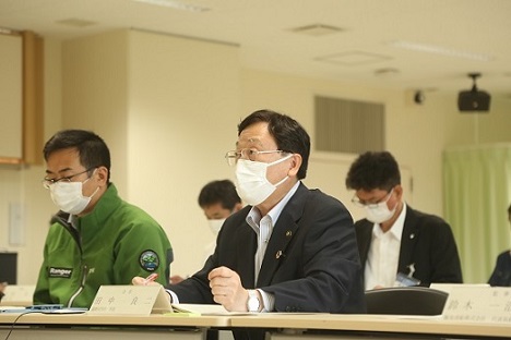 資料を確認しながら話を聞いている様子の男性たちの写真