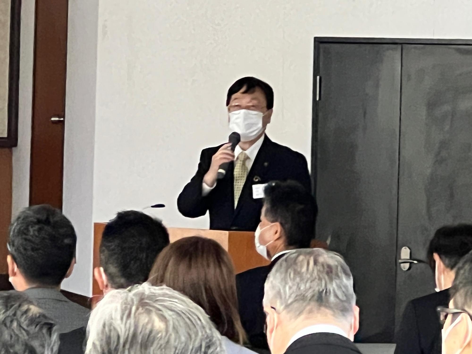午さん会で会場の参加者たちに向けてマイクを持って発言している市長の写真