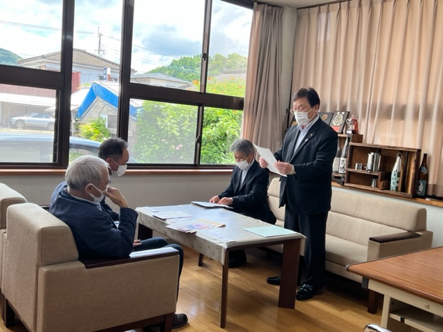 市内の商工会の代表2名に原稿を読み上げている市長と隣で座っている関係者の写真