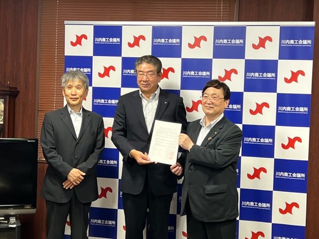 商工会議所で調印書を見せている市長と関係者の写真