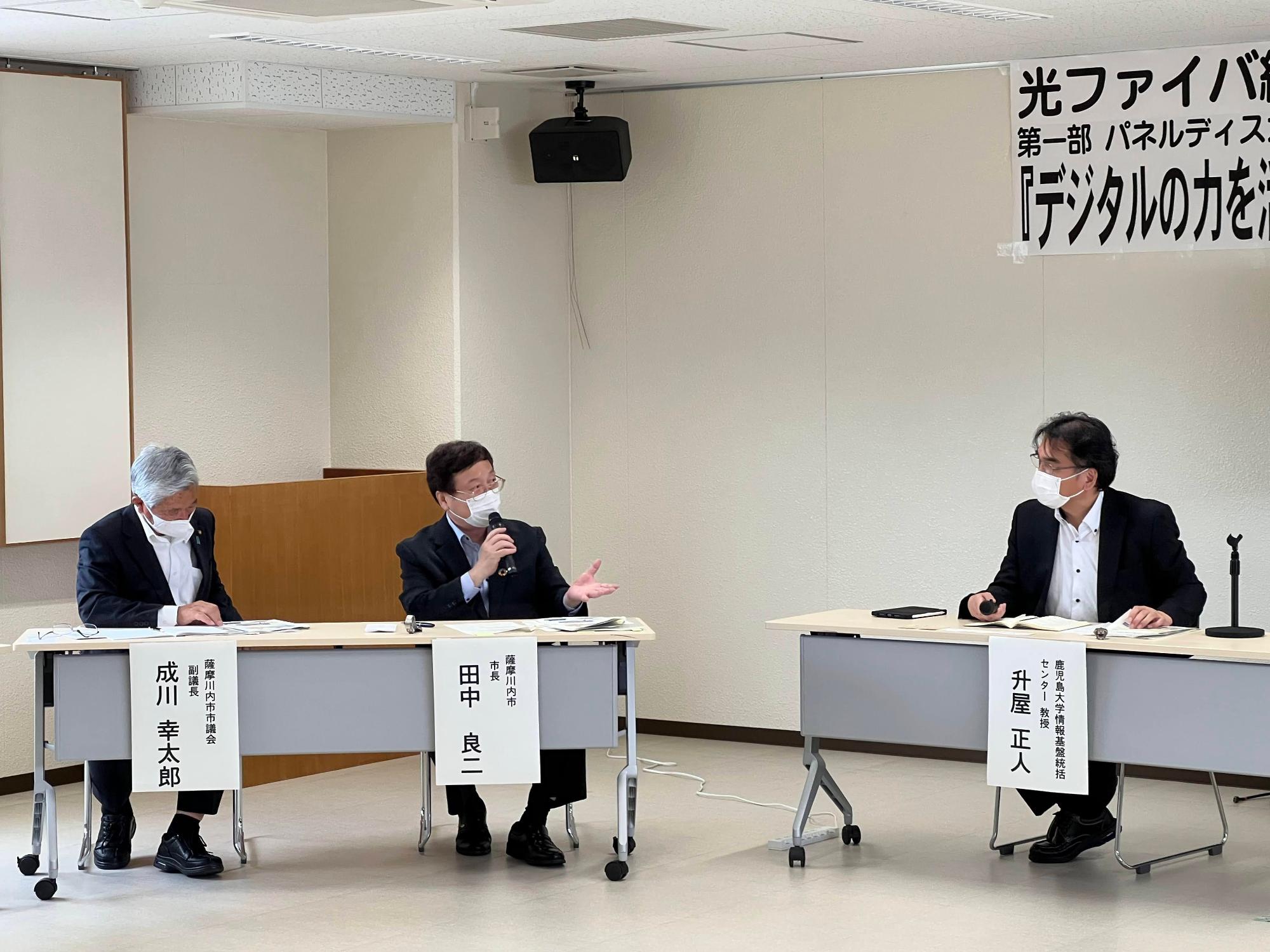 市長を中心に男性三人がパネルディスカッションをしている様子の写真