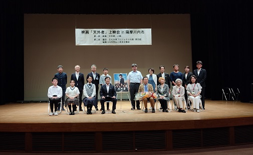 天外者のポスターを中心に、市長や高校生や映画関係者たちが並んでいる記念写真