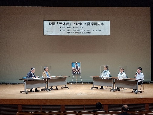 天外者のポスターを中心に、左側に座っている市長と関係者、右側に座っている3人の高校生たちが話し合っている様子の写真