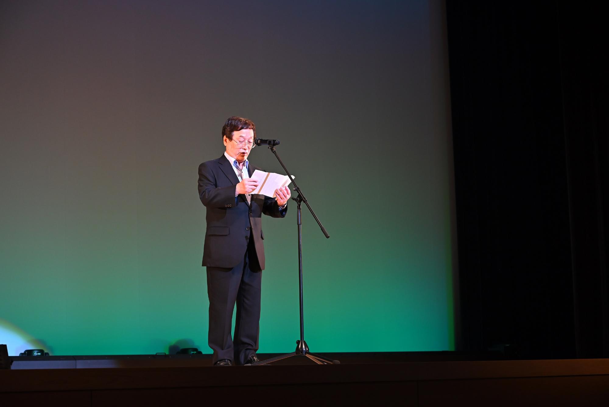 壇上で開会宣言の原稿を読んでいる市長の写真