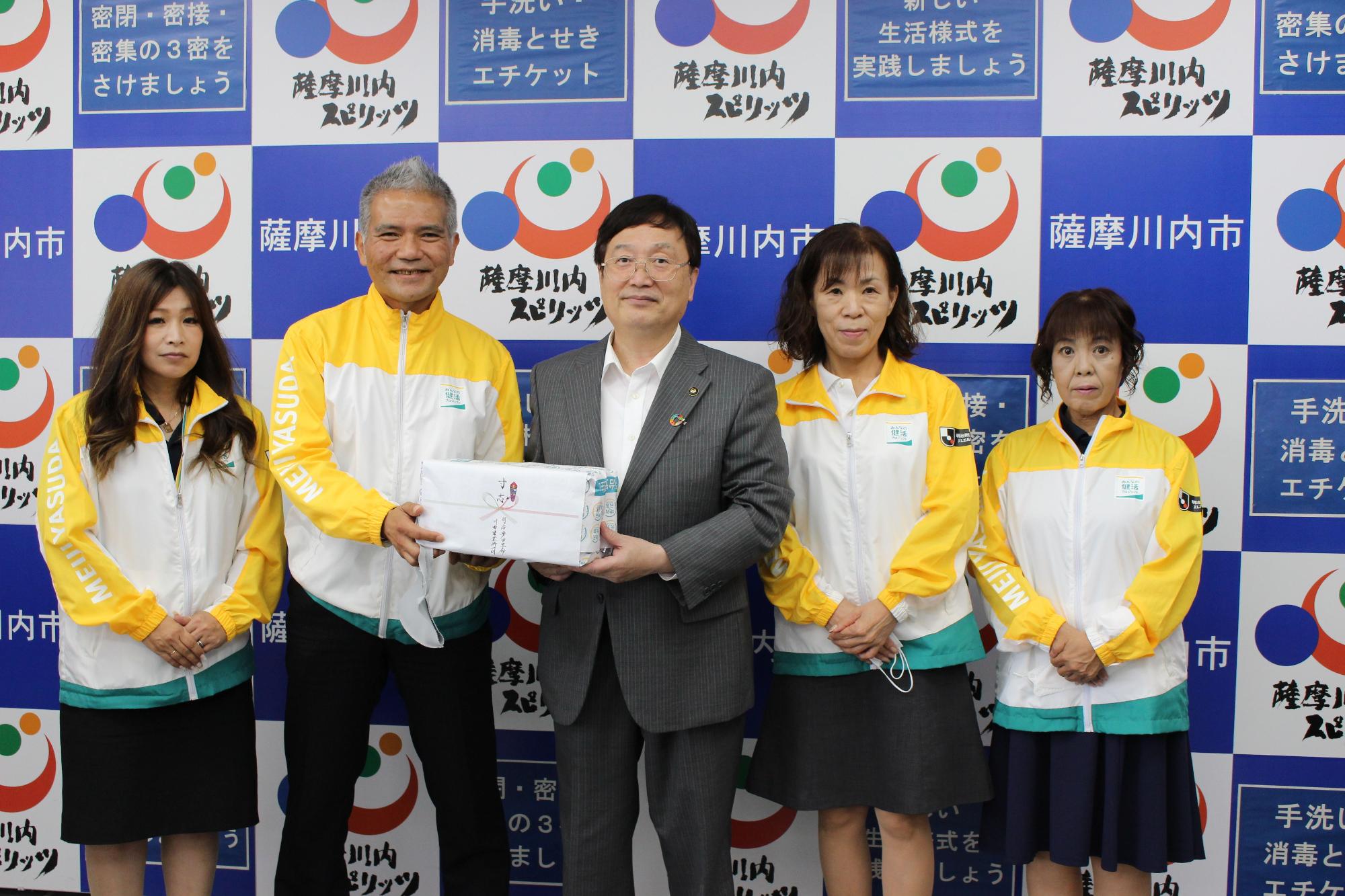 明治安田生命のジャージを着た男女と田中市長が並んでいる写真