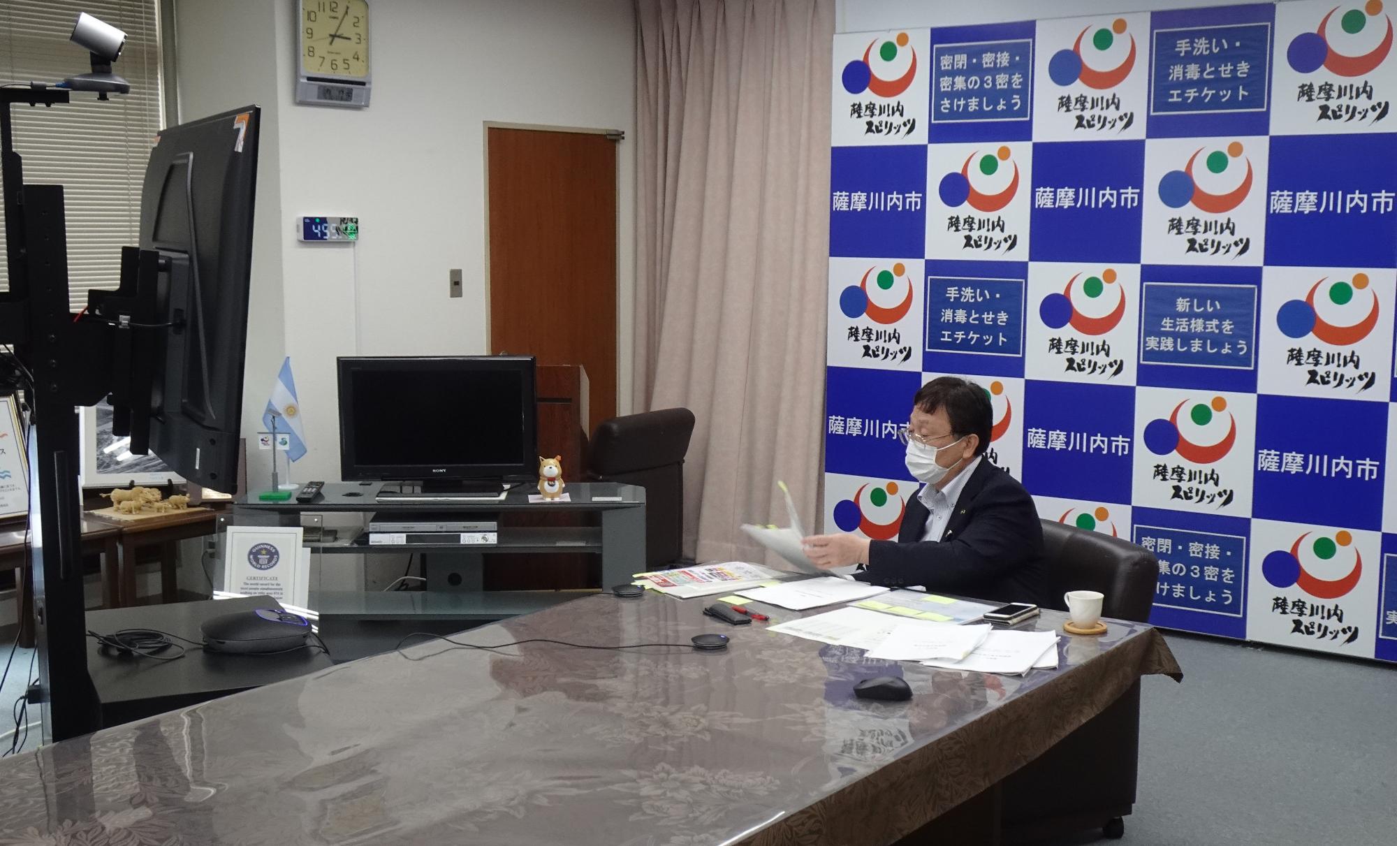 モニターの前で資料を確認している田中市長の写真