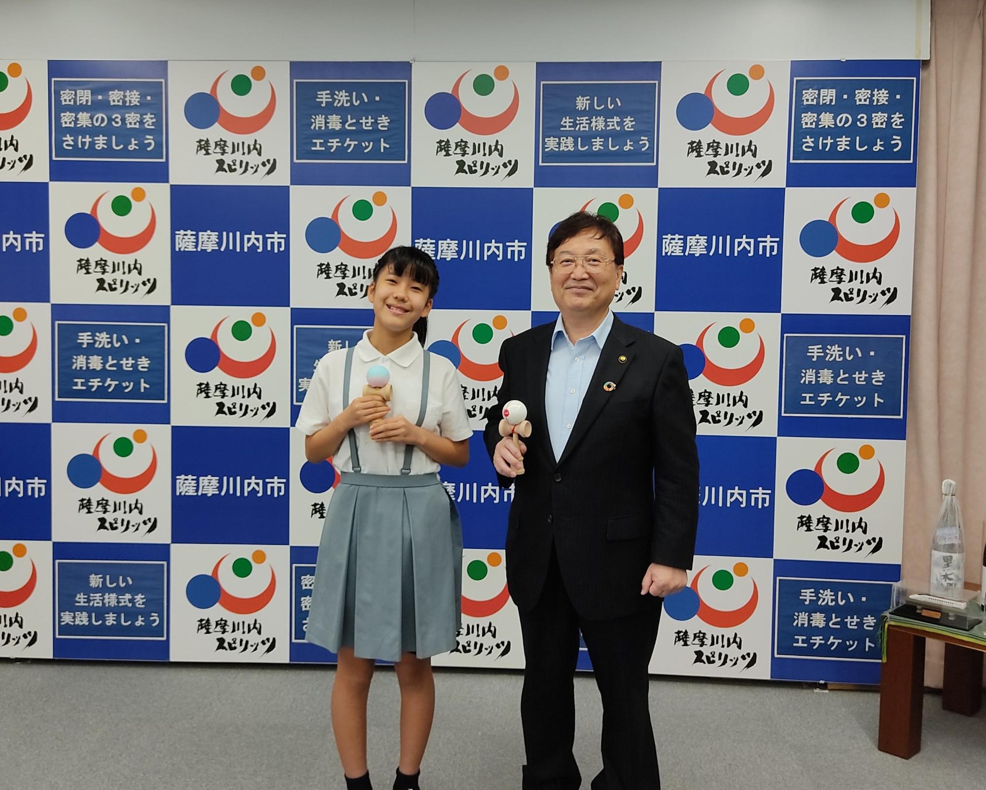 けん玉を持って並ぶスーツ姿の男性と女児の写真