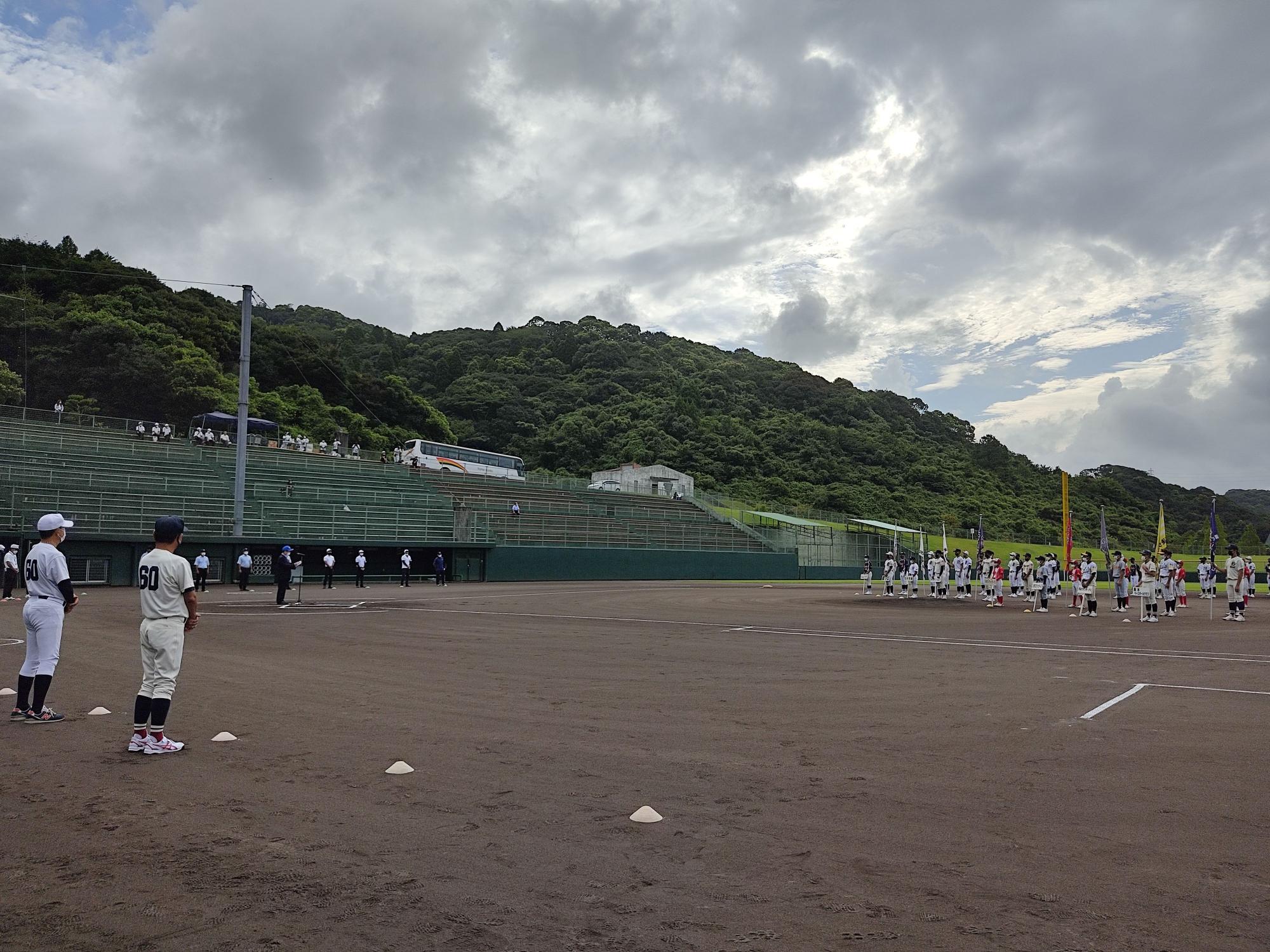 野球ユニフォームを着た学生たちがスペースを空けて整列している写真