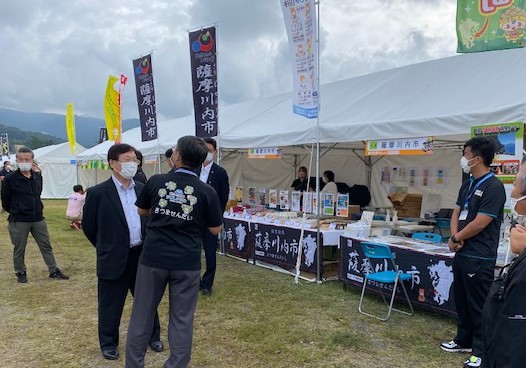 白いテントの前で談笑する男性たちの写真