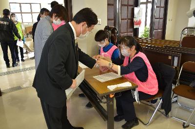 ワクチン接種の受付をする田中市長の写真