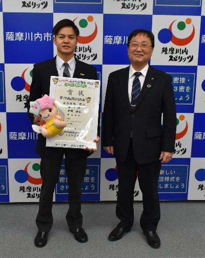 賞状を持って、並んで写真に写る新開選手と田中市長の写真
