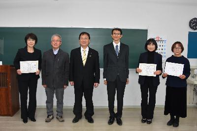 修了証を手に並んで写真に写る田中市長と受講生らの写真