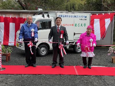 テープカットを行う田中市長と大馬越地区コミュニティ協議会の関係者らの写真