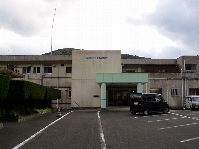 2階建てコンクリート造りの上甑診療所の建屋とミントグリーンの入口門を駐車場から写した写真