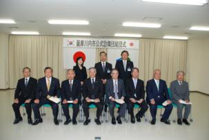 スーツ姿の男性たちが横一列に座っている写真