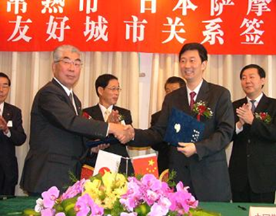 平成17年の再調印式でスーツ姿の男性二人が握手をしている写真