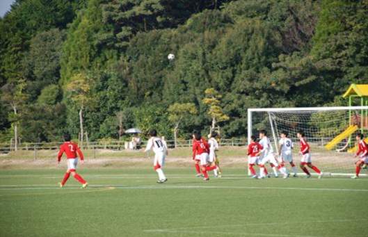 赤いユニフォームと白いユニフォームを着た子供たちがサッカーをしている写真