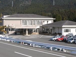 道路の向こう側に白い二階建ての建物が見える写真