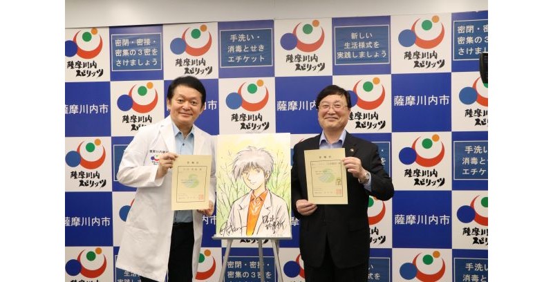 白衣を着た男性とスーツ姿の男性が、漫画に出てくる外科医のキャラクターがかかれたキャンバスの隣で表彰を持っている写真