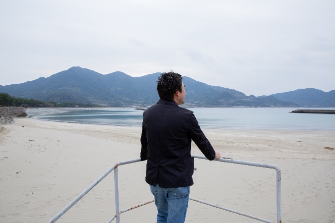 白い砂浜と玉砂利がとても美しい「西の浜海岸」にて移住当初の思い出を語ってくれた伊原さん