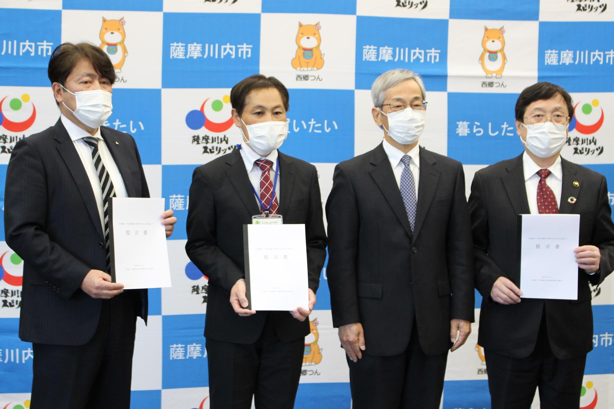 スーツ姿の男性たちが書類を掲げて持っている写真