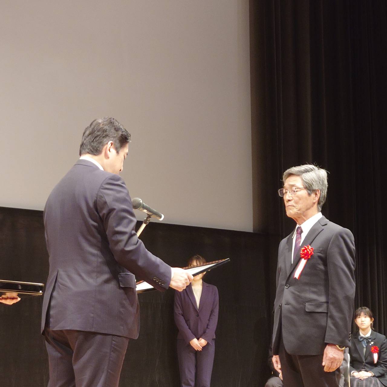 令和5年度鹿児島県共生・協働型地域コミュニティづくり推進優良団体表彰式で奨励賞の賞状伝達を行う鹿児島県知事と鳥丸地区コミュニティ協議会長を写した写真