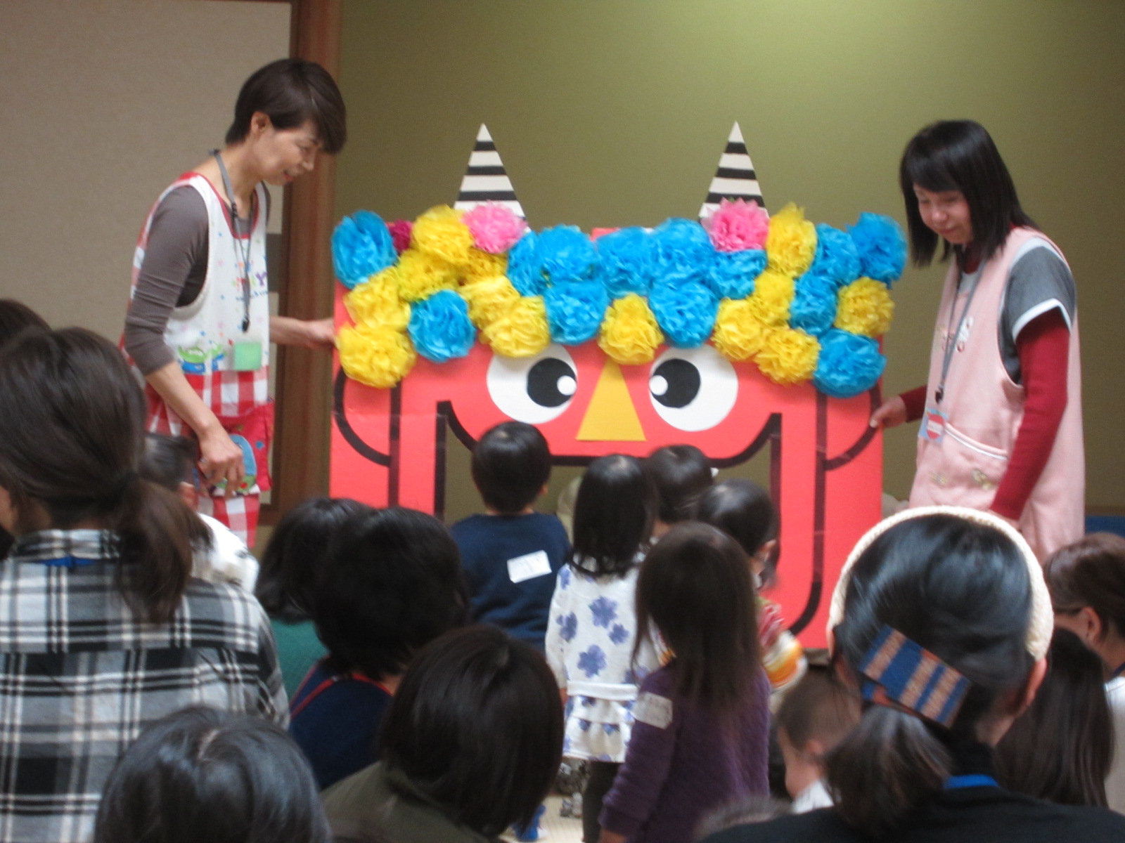 大人の背丈ほどある鬼の顔の工作に子供たちが集まっている写真