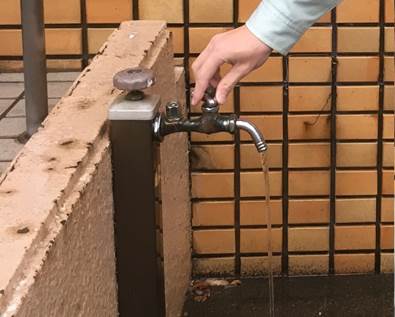 水道の蛇口をひねって少し水を出している様子を捉えた写真