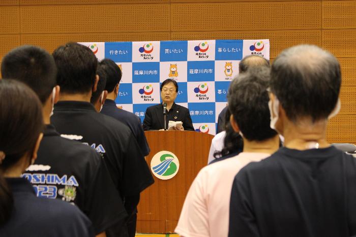 会場で選手らの前で挨拶をする田中市長の写真