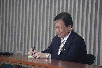 目を閉じ文字を書いている田中市長のようす