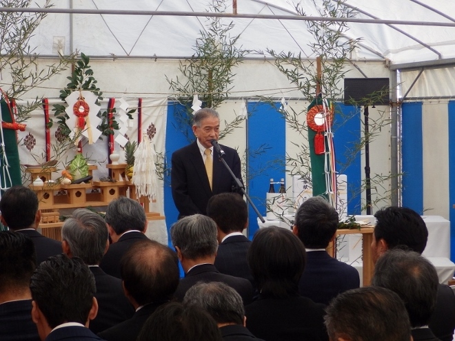 竹などが飾られている会場でスーツ姿の男性がスタンドマイクを使って話している写真