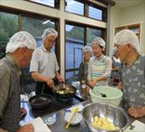 白いネットキャップを被った男性たちが料理をしている写真