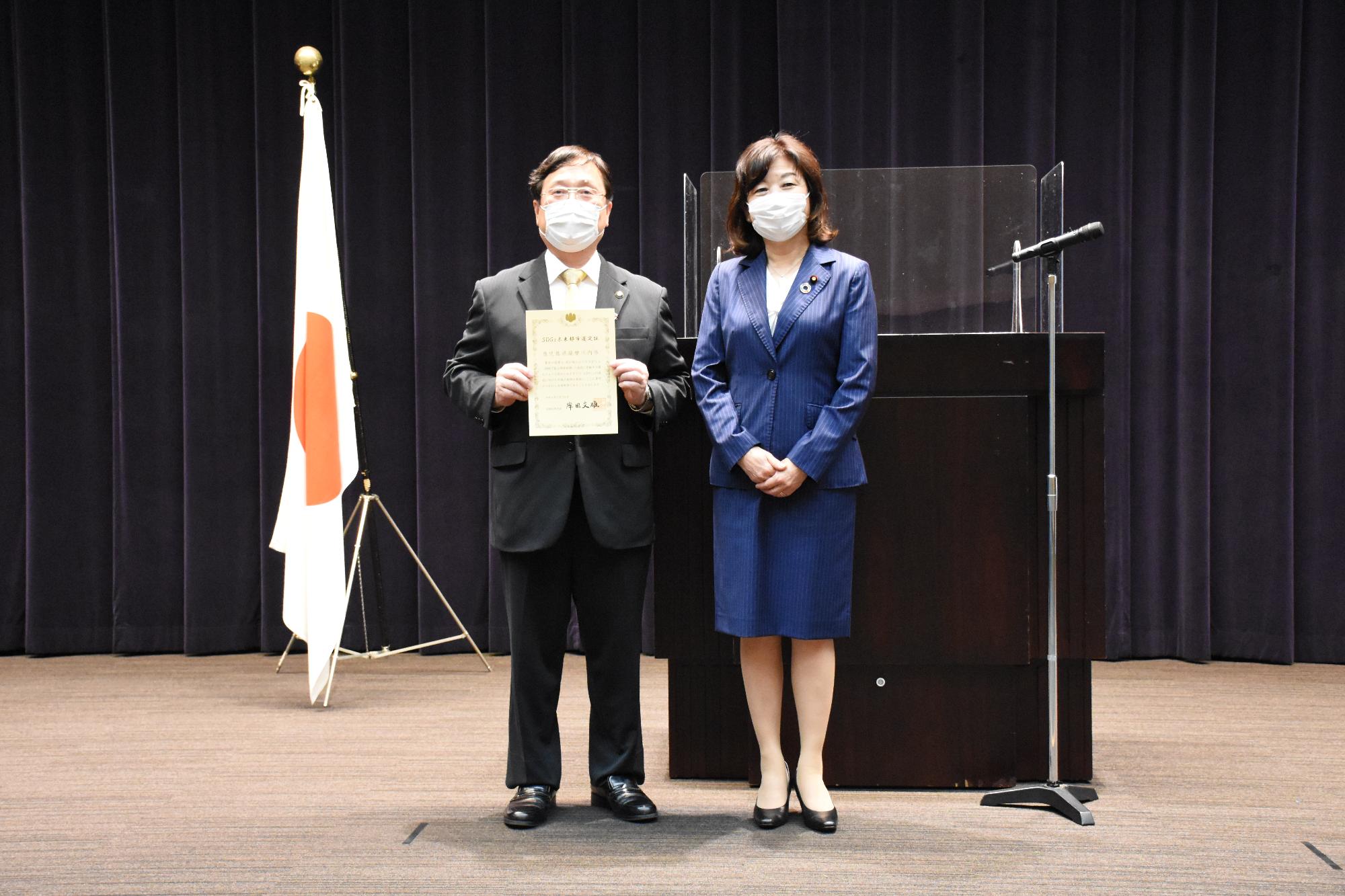 選定証授与式で田中市長と野田地方創生担当大臣が並んでいる写真