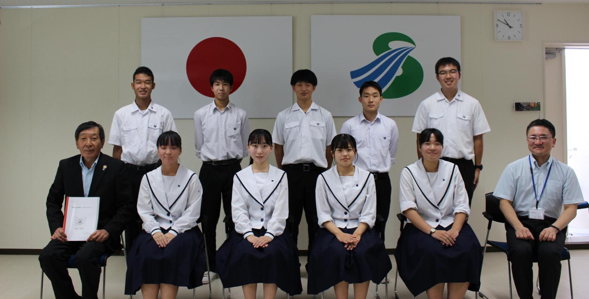 日の丸と薩摩川内市旗が掛けられた室内で、賞状を持った男性1名と、半袖シャツの中年男性1名、女生徒4名が前方に座り、男子生徒5名が後ろに立っている記念写真