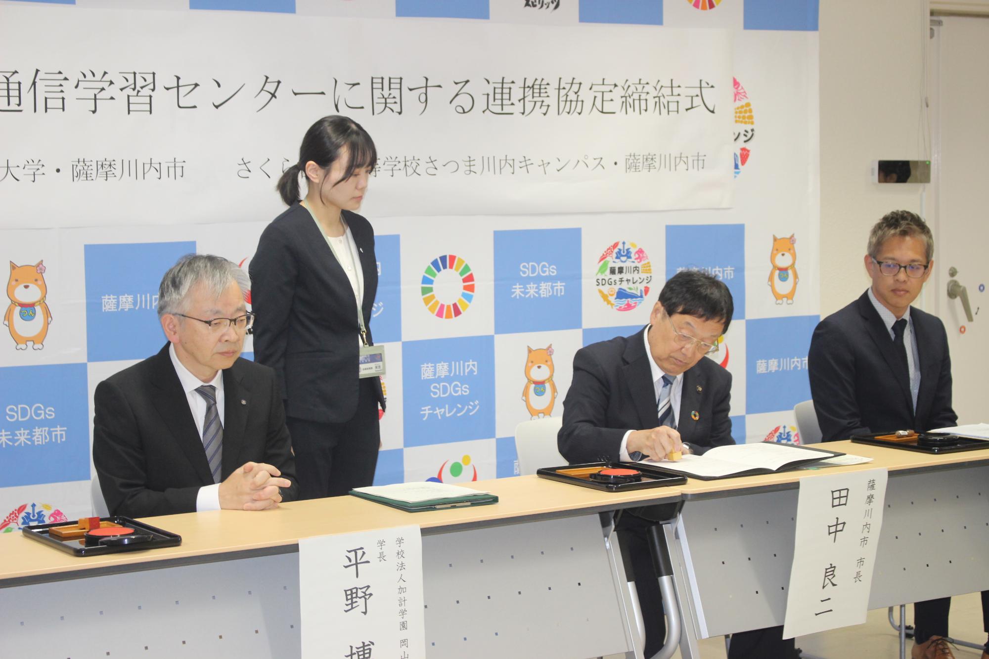 田中市長が調印する様子