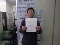 宣言文を手に持って正面に向けている西日本興業株式会社の代表取締役 新添 吉正の写真