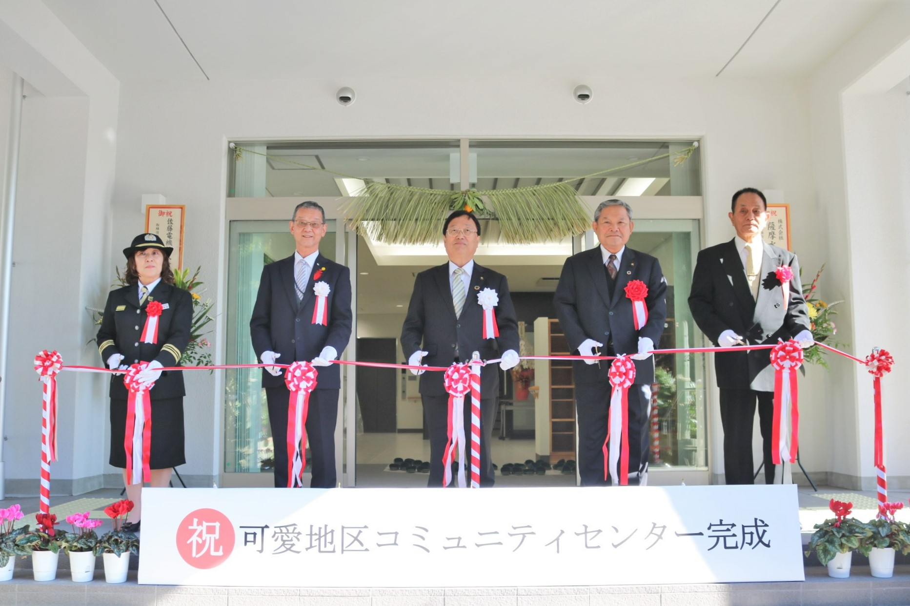 新築された可愛地区コミュニティセンターの玄関で薩摩川内市長、議長、教育長、コミュニティ協議会長、消防団長の5名でテープカットを行う写真