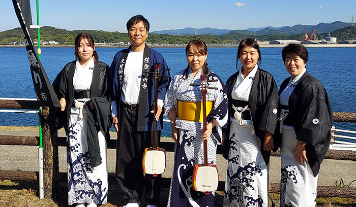 久見崎盆踊り保存会での活動の写真、男性1名が法被姿で三味線を持ち、女性4名が浴衣を着てそのうち1名が三味線を持っている