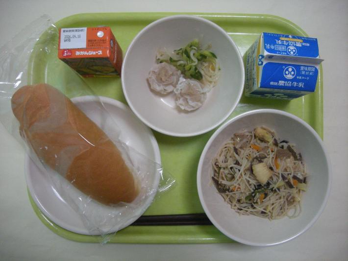 コッペパン（幼稚園ロールパン）、焼きビーフン、しゅうまい（幼稚園1個、小中学校2個）、中華風添え野菜、みかん果汁、牛乳の写真
